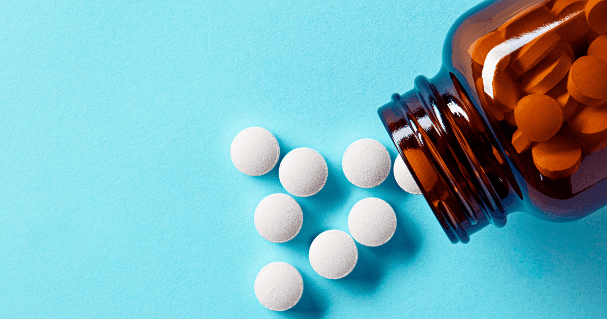 Anti seizure medication: A brown pill bottle on its side with white pills spilling out against a blue background