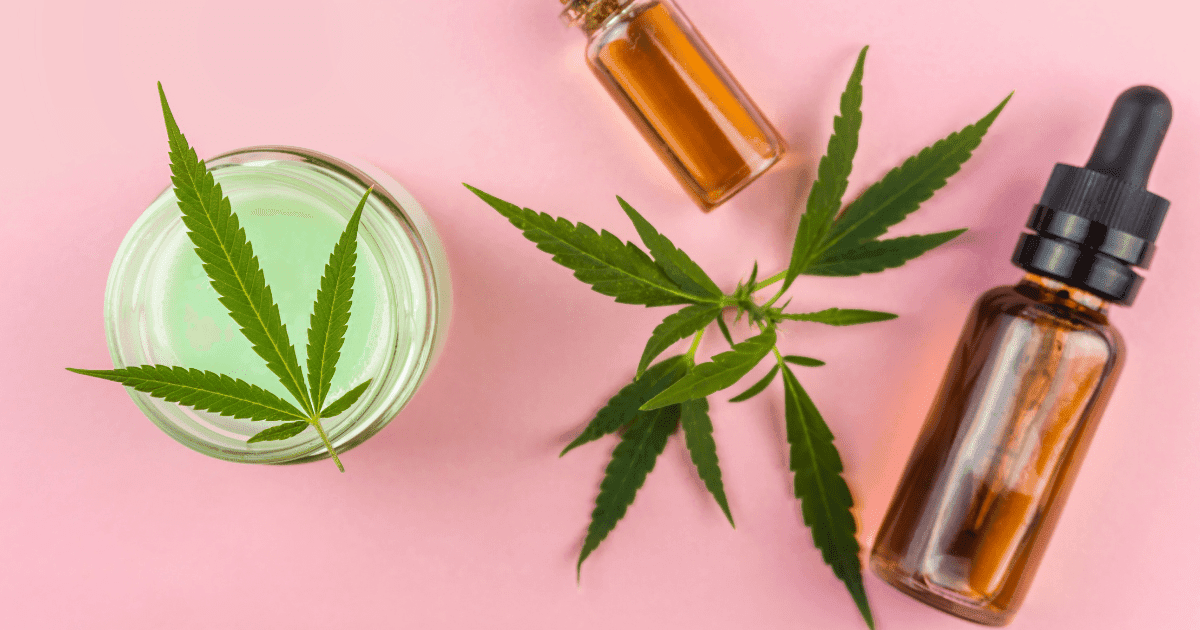 CBD beauty: A cream with a cannabis leaf on top sits next to two bottles of brown oil with another leaf on a pink background