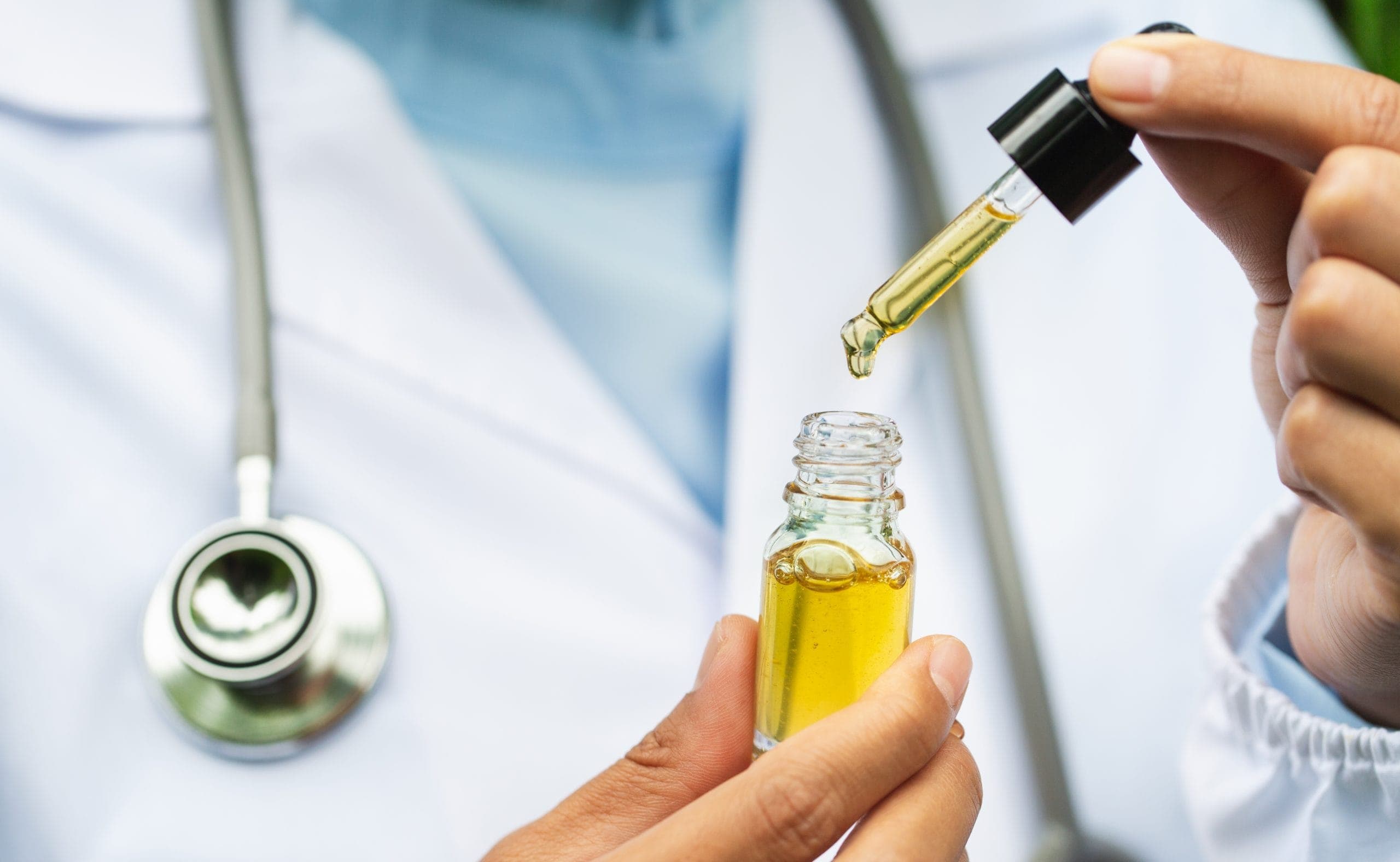 MCAP programme: neurologists holds a yellow bottle of oil with a dropper against a lab coat