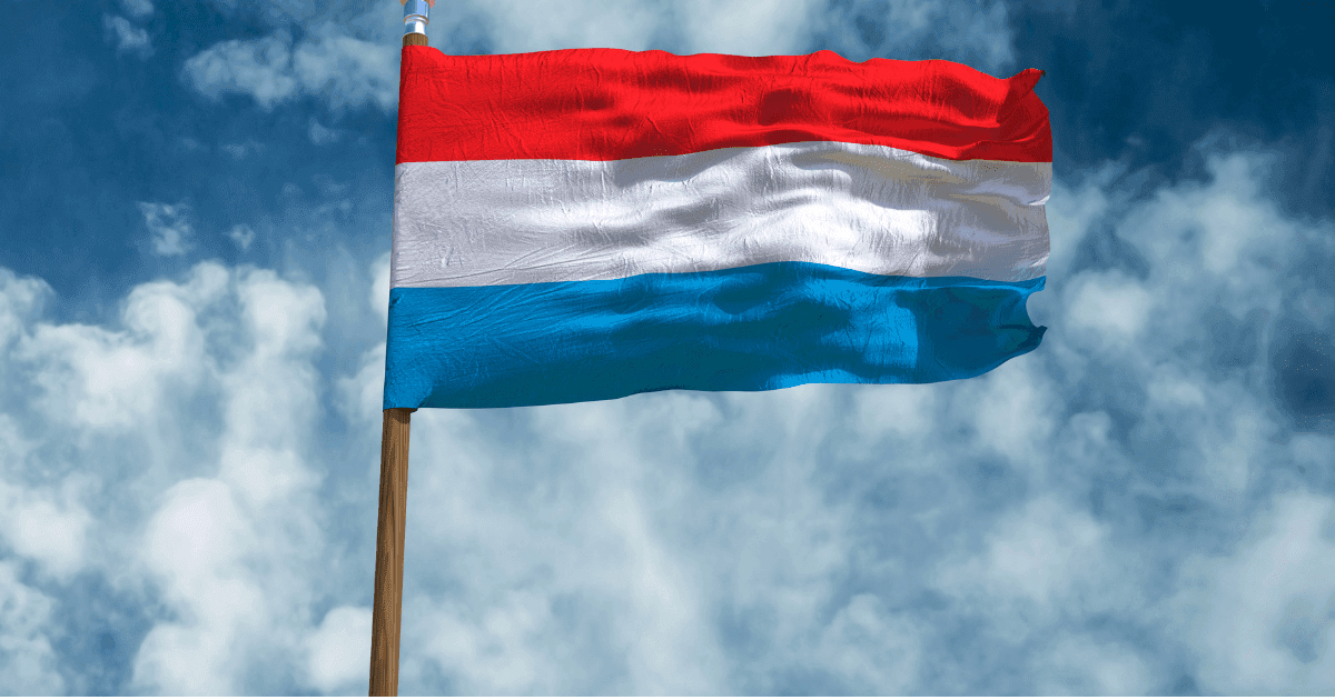 Luxembourg: A flag with red, white and light blue stripes fluttering against a blue sky with white clouds