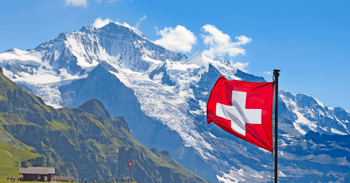 Zurich: A red and white swiss flag against the blue sky of Zurich with mountains