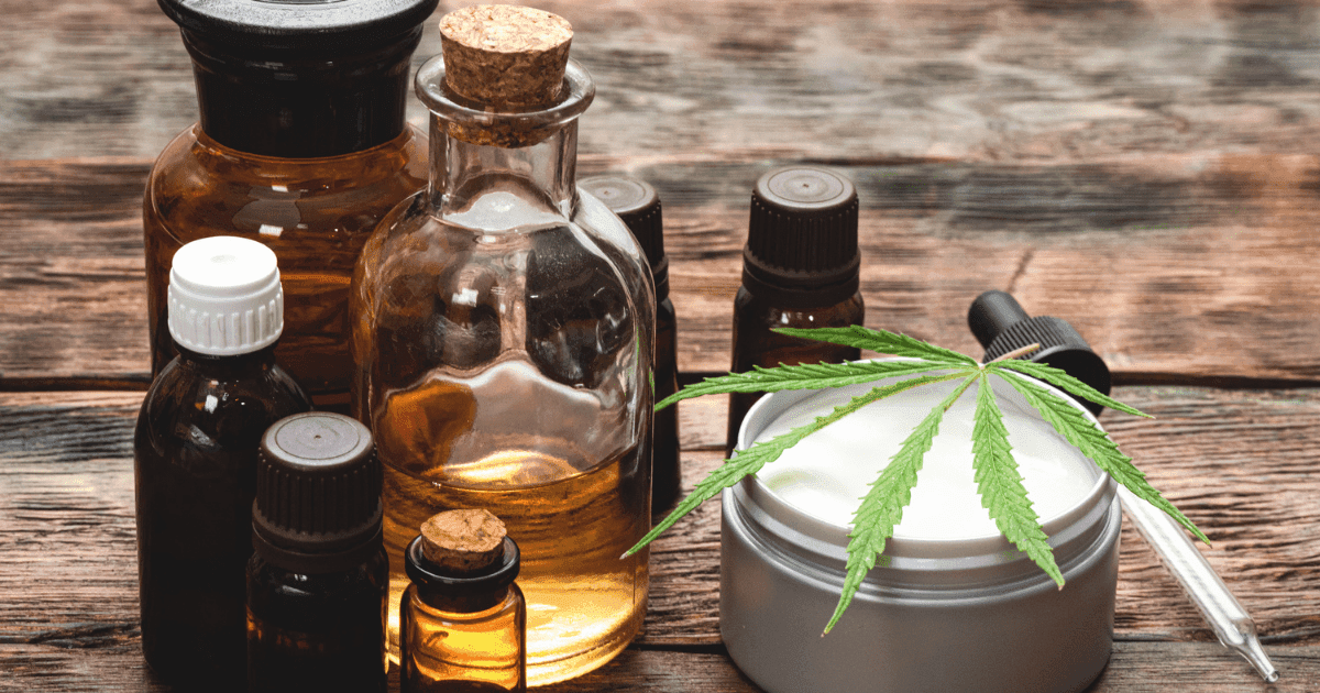 Autism: A collection of clear glass and brown tincture bottles together on a wooden surface next to a balm that has a cannabis leaf on it.