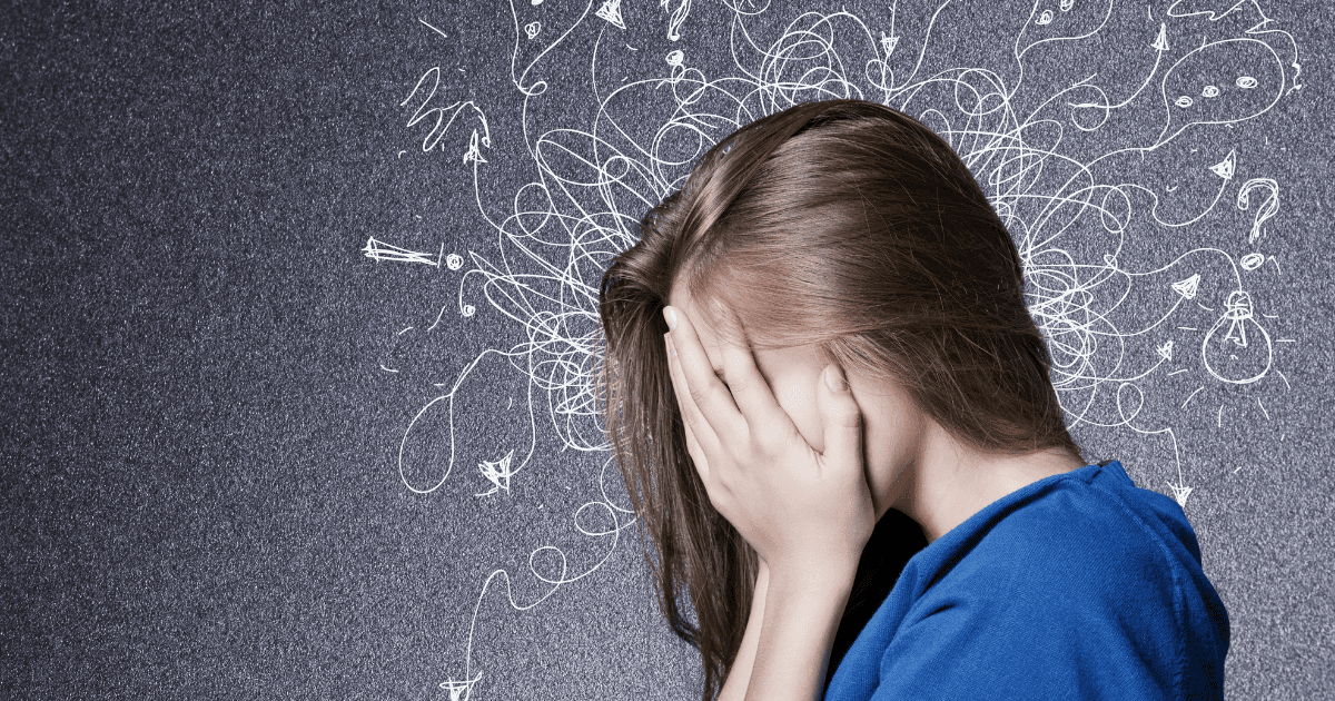 Endocannabinoid: A woman with her head in her hands wearing a blue top against a blue background. The background has white lines to highlight anxiety