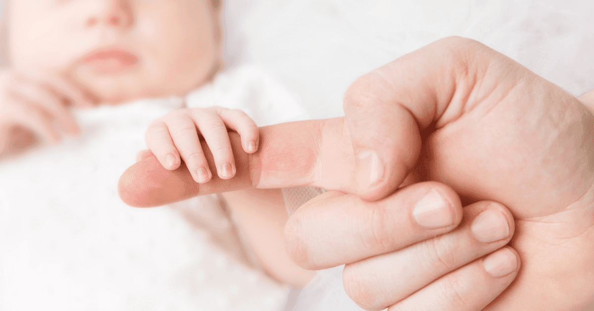 Neonatal: A baby holding a person's finger