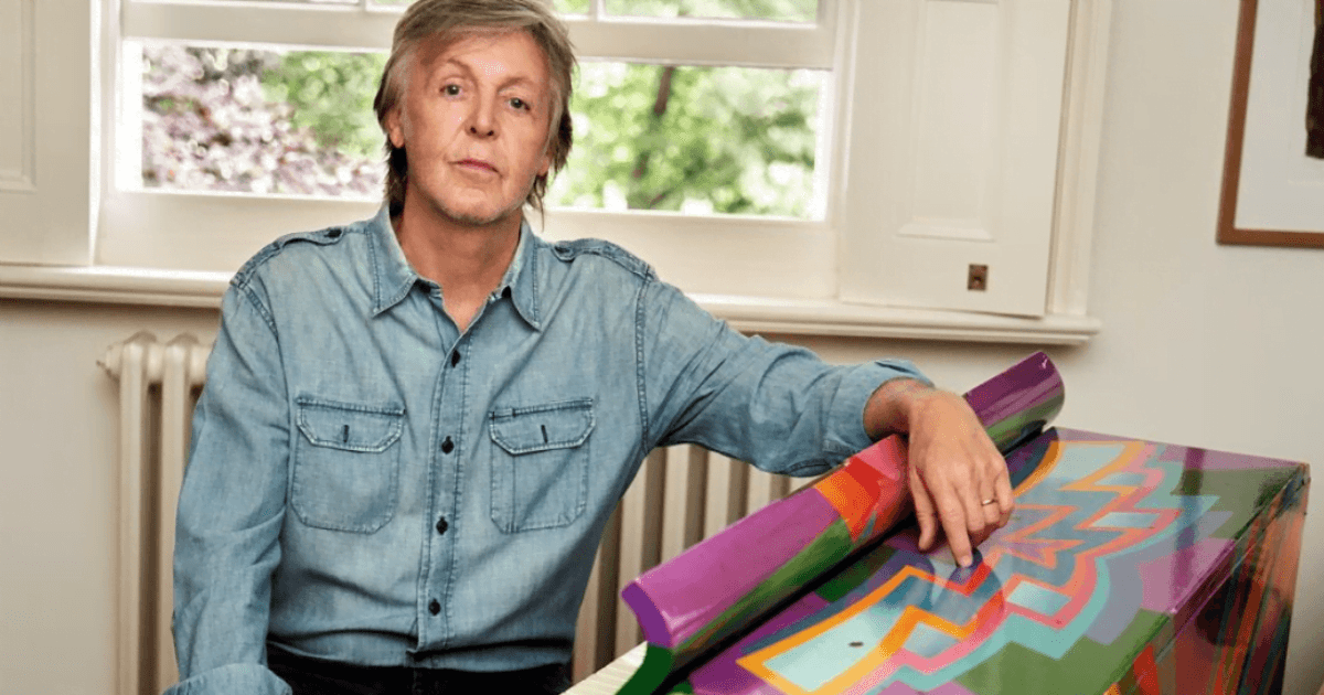 Paul McCartney: The Beatles musician wearing a denim blue shirt poses next to a multicoloured artwork