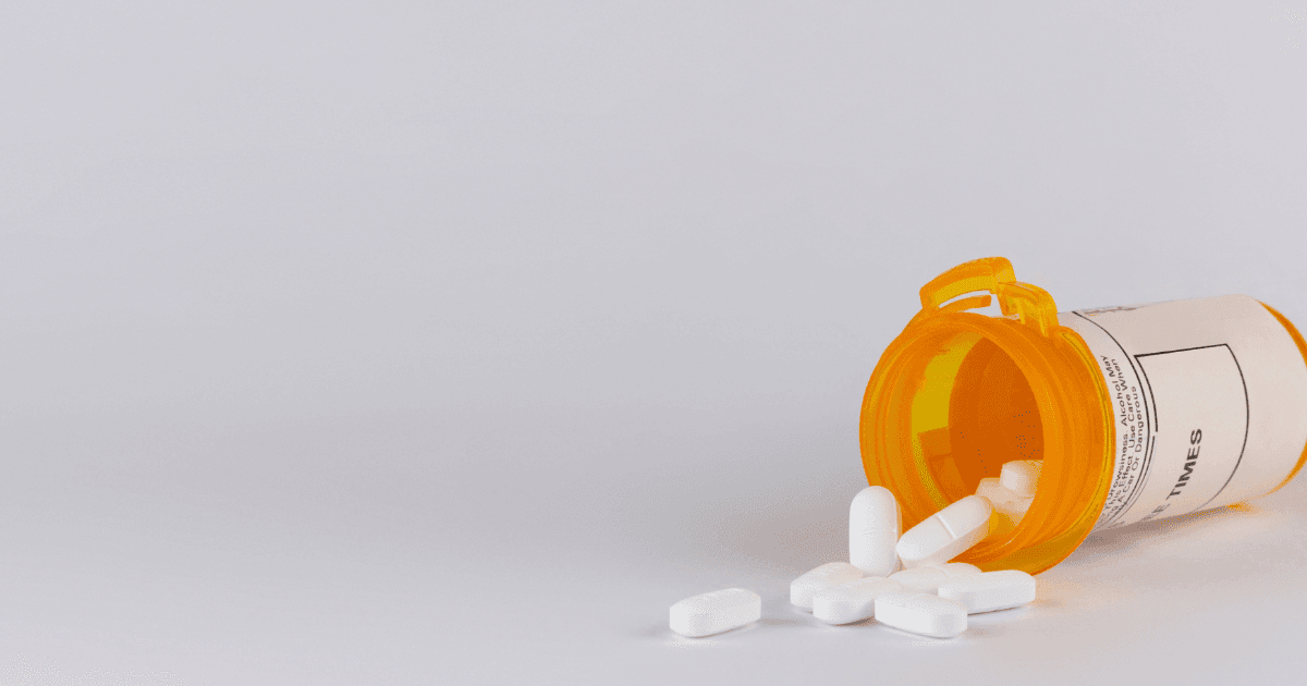 Pain: A bottle of opioids on their side spilling white tablets onto a counter
