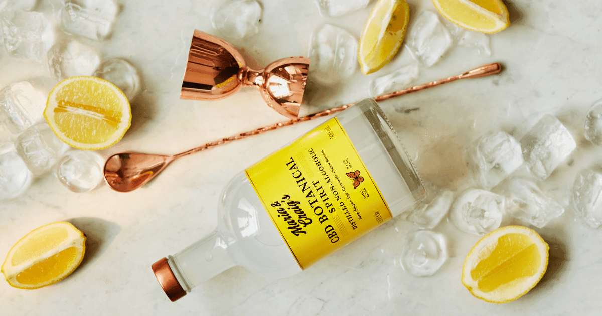 Drink: A bottle of Maria and Craig's on a surface surrounded by rose gold drink accessories, lemon slices and ice cubes for making a drink