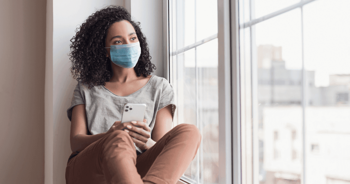 Australia: A woman sits in a window watching the outside world with a mask on
