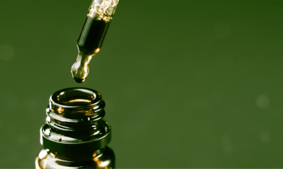 Article: The top of a bottle with a dropper about to pour oil in against a green background