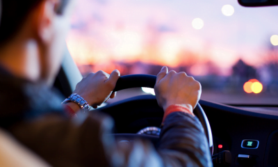 Driving and CBD: A man's hands on the steering wheel of a car against a sunset