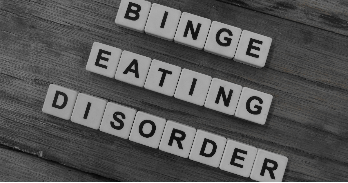 Binge eating: Scrabble tiles spelling out binge eating disorder on a wooden floor