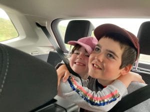 Article: A young boy and a girl hug in the back of the car.