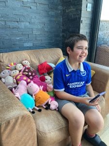 Article: A boy sits on a couch surrounded by toys