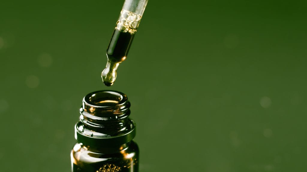 Medical cannabis report: A green background showing the top of a CBD bottle with a yellow dropper dripping liquid into the bottle