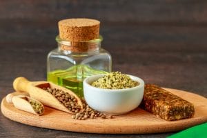 Climate change and food: a bowl of hemp seeds on a wooden board next to a small bottle of yellow oil.
