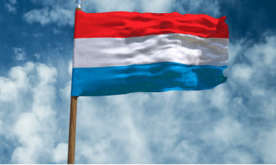 Luxembourg: A flag with red, white and light blue stripes fluttering against a blue sky with white clouds