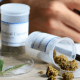 California: Two white tubs of medical cannabis on a wooden surface. A doctor is writing a prescription
