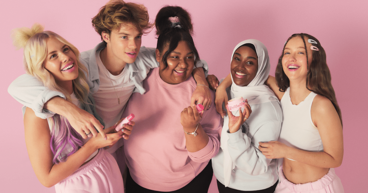 Gen-Z: A group of young people hug in front of a camera while all are wearing a light pink colour.
