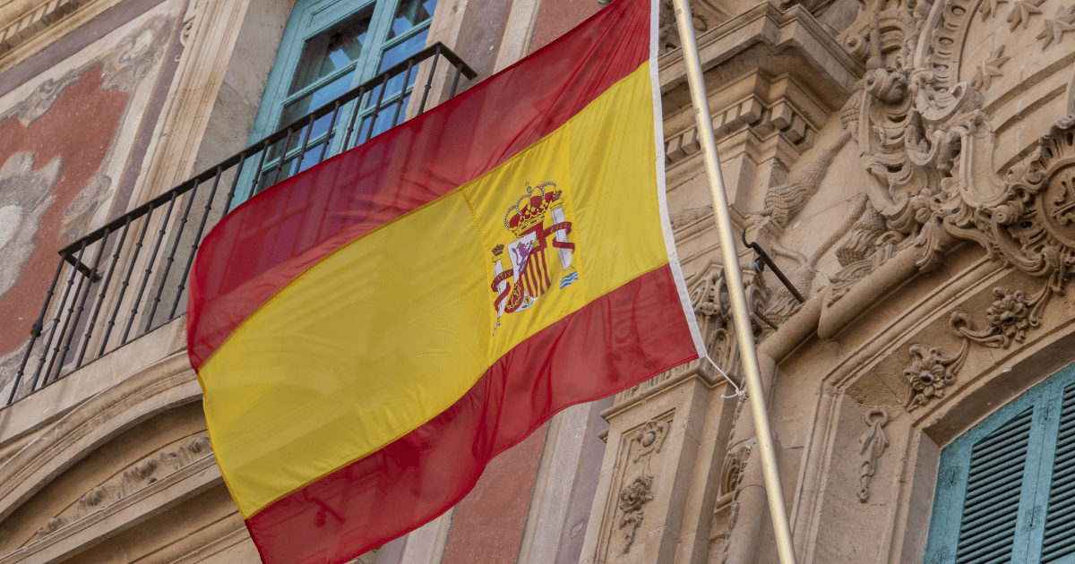 Spain cannabis: A Spanish flag in the air with an old building behind it