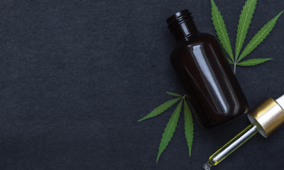 Trigeminal Neuralgia: A bottle of CBD oil against a dark background with two cannabis leaves beside it.