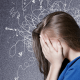 Endocannabinoid: A woman with her head in her hands wearing a blue top against a blue background. The background has white lines to highlight anxiety