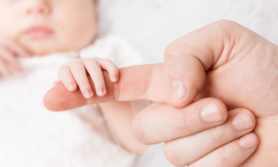 Neonatal: A baby holding a person's finger
