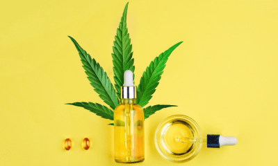 Juicyfields: A cannabis leaf with a small bottle of oil, two capsules, a jar and a dropper of oil on a yellow background