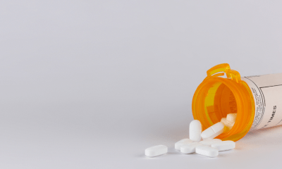 Pain: A bottle of opioids on their side spilling white tablets onto a counter