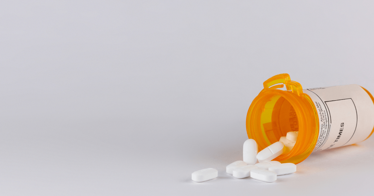 Pain: A bottle of opioids on their side spilling white tablets onto a counter