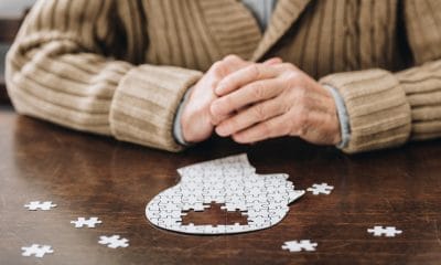 Alzheimer’s: cropped view of senior man playing with puzzles on table