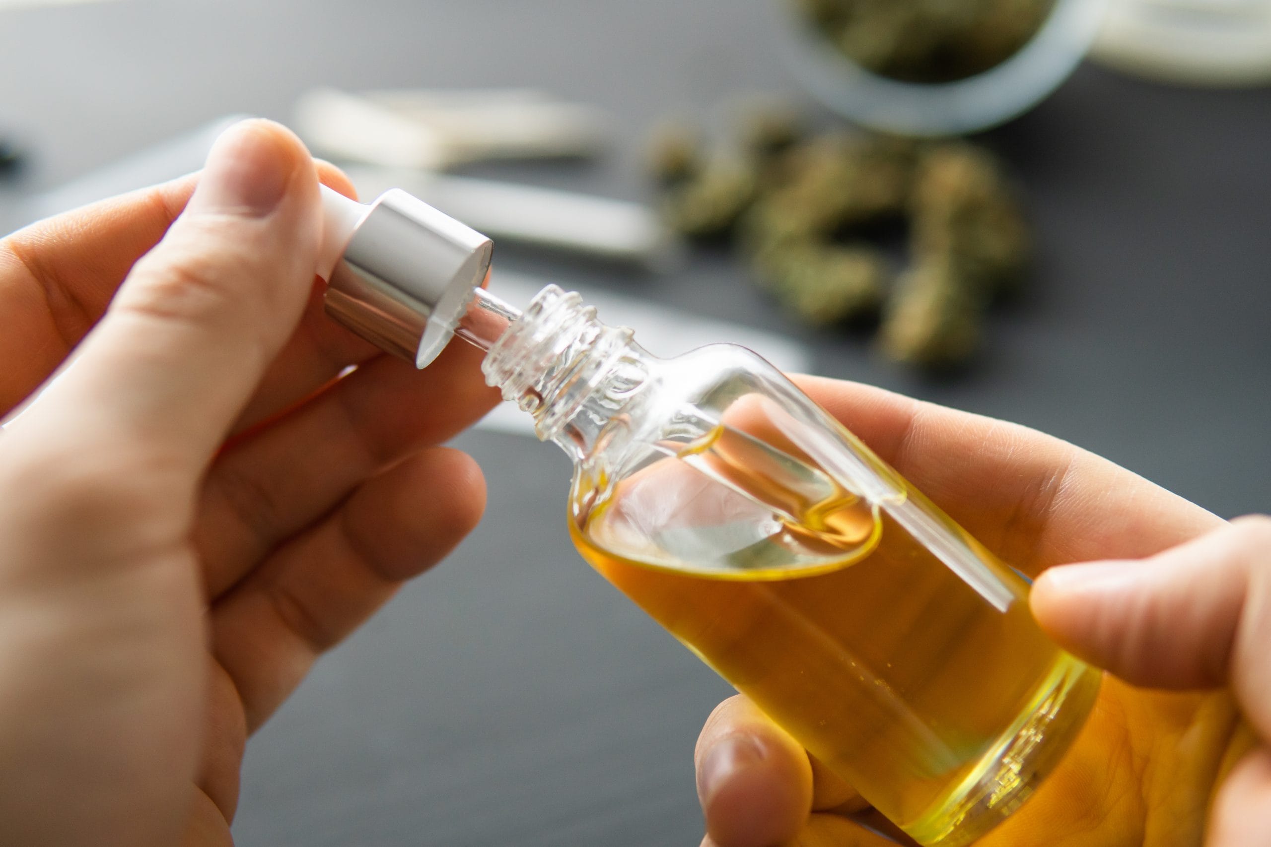 Fibromyalgia: A bottle of yellow CBD oil in a person's hands as they open the bottle